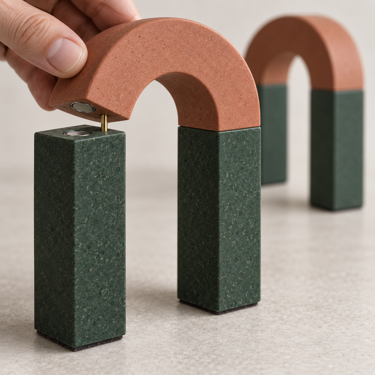 Magnetway Modular Arch Bookends - detail hand lifting terracotta arch from green column showing magnetic join
